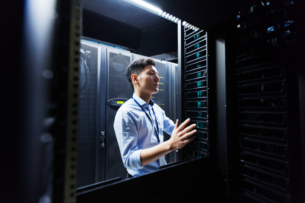 Young IT engineer inspecting data center servers